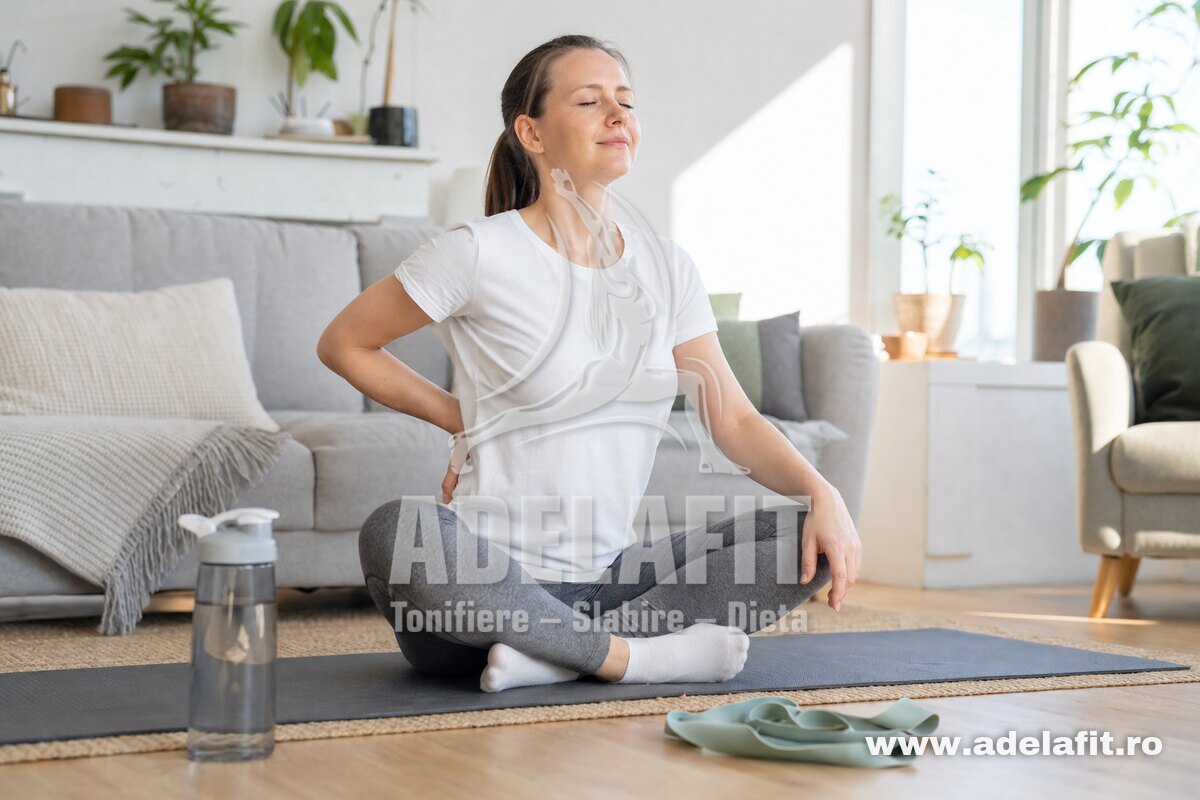 Femeie relaxată pe saltea acasă, meditând și pregătită pentru exerciții pentru spate